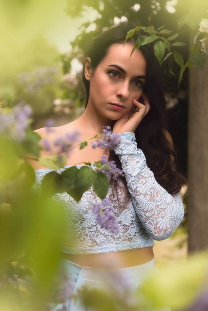 Beautiful young woman in a summer garden with lavender coloured flowers - Foto, Imagen