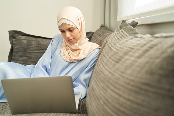 Muslim woman working on notebook at home - 写真・画像