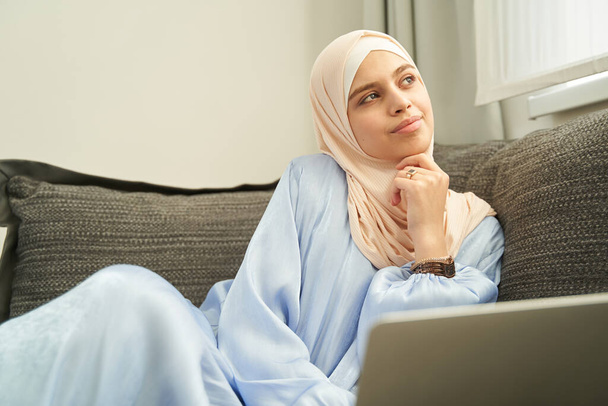 ムスリム女性座っています上のソファ-ホーム - 写真・画像