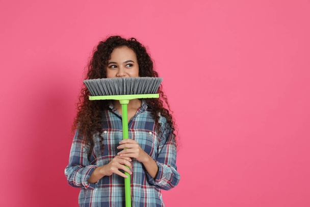 African American woman with green broom on pink background, space for text - Fotografie, Obrázek