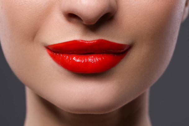 Young woman with beautiful red lips on grey background, closeup - Zdjęcie, obraz