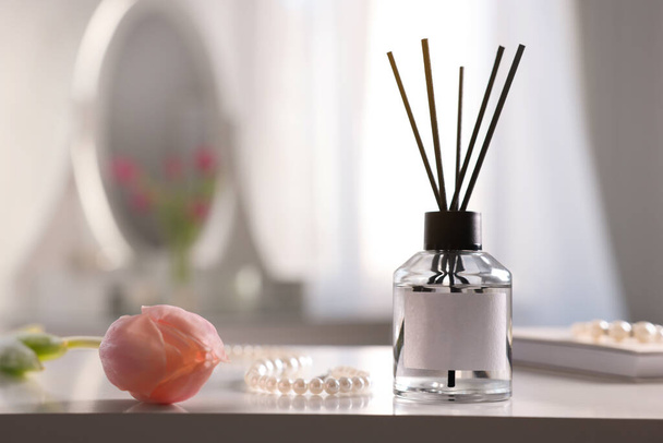 Reed diffuser, beautiful flower and pearl necklace on white table indoors. Space for text - Фото, изображение