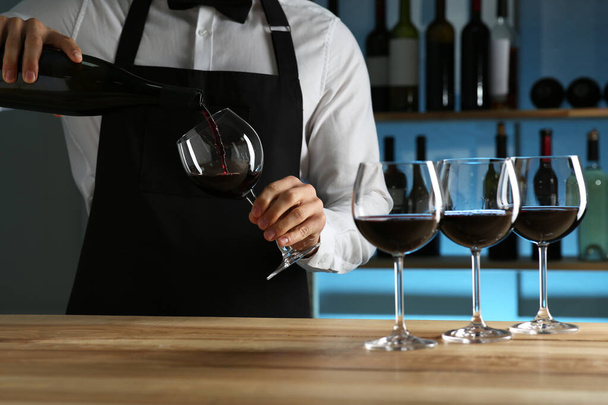 Bartender pouring wine into glass at counter in restaurant, closeup - 写真・画像