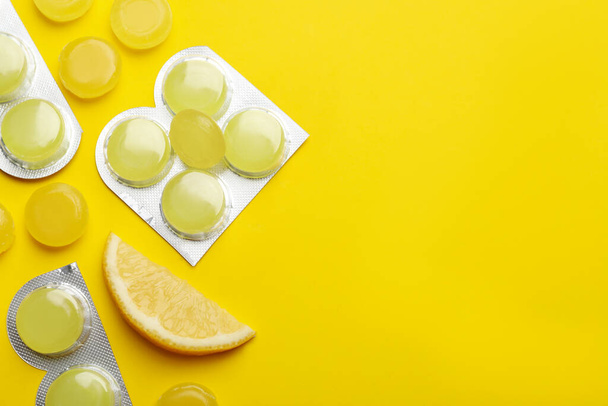 Many lemon cough drops on yellow background, flat lay. Space for text - Photo, Image