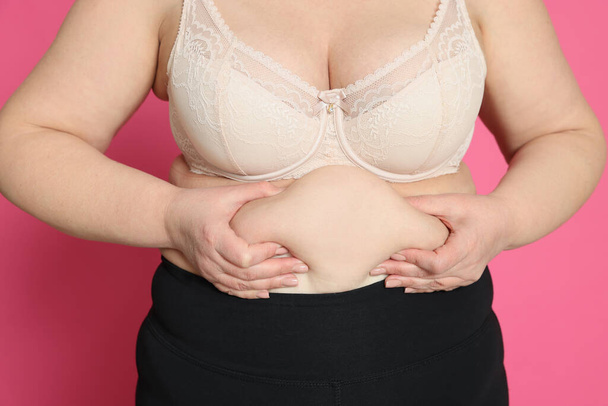 Obese woman on pink background, closeup. Weight loss surgery - Foto, Bild