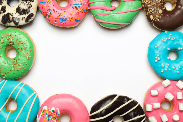 Different delicious glazed doughnuts on white background, top view. Space for text - Foto, Bild