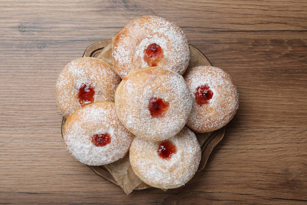 Delicious donuts with jelly and powdered sugar on wooden table, top view - Foto, Imagen