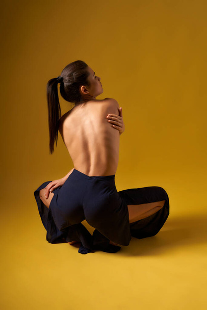 Girl with bare back doing yoga indoors. - Foto, imagen