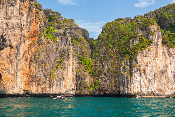 Touristisches Holzboot auf kristallklarem Wasser mit wunderschönem Karstberg in der Nähe der Monkey Bay auf der Insel Phi Phi, Krabi, Thailand. Berühmtes Reiseziel oder Sommerurlaub in Siam. - Foto, Bild