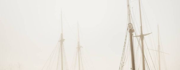 Elegáns és modern jachtok, vitorlás és halászhajók kikötve ti egy mólón a köd. Schooner közelkép. Látványosságok, városnézés, régi kikötő, történelem, múlt. Sepia-kép effektus. Germaniahafen, Kiel, Németország - Fotó, kép