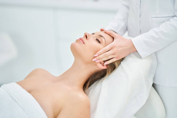 Jovem mulher agradável tendo massagem facial no spa - Foto, Imagem