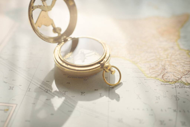 Retro style antique golden compass (sundial) and old nautical chart close-up. Vintage still life. Sailing accessories. Wanderlust, travel and navigation theme. Graphic resources, copy space - Foto, Imagem