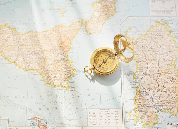 Retro style antique golden compass (sundial) and old nautical chart close-up. Vintage still life. Sailing accessories. Wanderlust, travel and navigation theme. Graphic resources, copy space - Foto, afbeelding