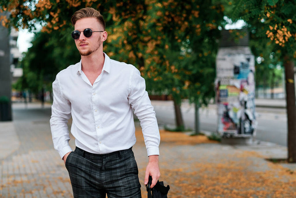 Молодий виконавчий бізнесмен носить сонцезахисні окуляри, стоячи на вулиці
. - Фото, зображення