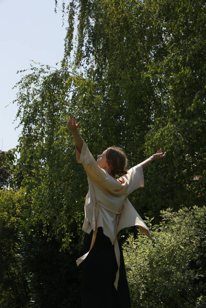 Outdoor serie of imges of young woman in beige silk kimono and wide black trousers in the public park - Foto, immagini