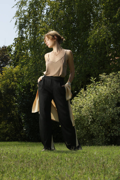 Outdoor serie of imges of young woman in beige silk kimono and wide black trousers in the public park - Foto, afbeelding