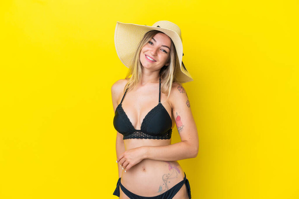 Giovane donna rumena isolata su sfondo giallo in costume da bagno nelle vacanze estive - Foto, immagini
