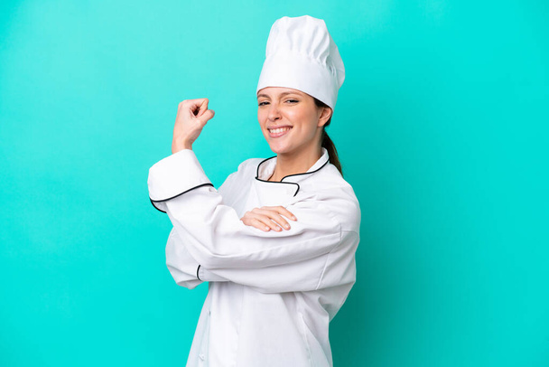 Young caucasian chef woman isolated on blue background doing strong gesture - Foto, Imagen