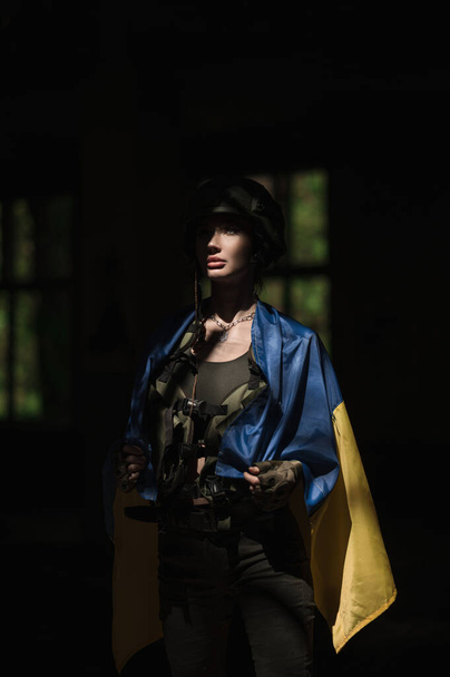 Military Ukrainian girl takes cover with the national blue-yellow flag of Ukraine - Photo, image