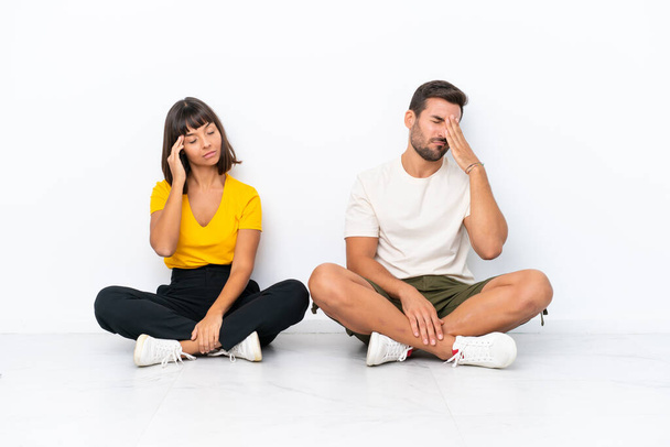 Young couple sitting on the floor isolated on white background unhappy and frustrated with something - Photo, Image