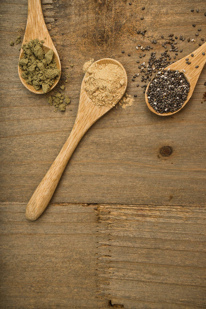 Rustic composition of superfoods on wooden spoons. Maca, Chia and Hemp Protein all of them sources of vitamins and omega-3. Healthy lifestyle and diet concept. Top view. - Photo, image