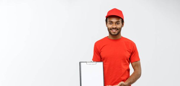 Delivery Concept - Portrait of Handsome African American delivery man or courier showing a confirmation document form to sign. Isolated on Grey studio Background. Copy Space. - Fotografie, Obrázek