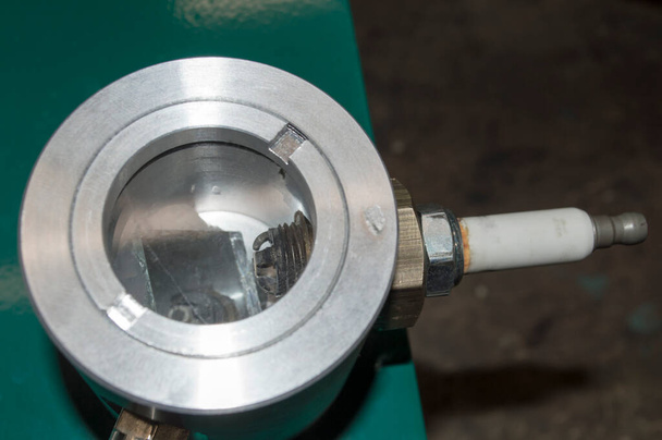 Vonk stekker geïnstalleerd in de drukkamer van de groene standaard voor het controleren van bougies van benzine verbrandingsmotoren - Foto, afbeelding