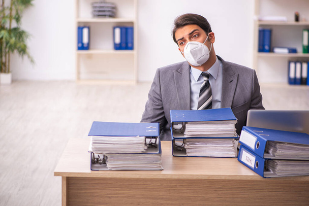 Jeune employé masculin travaillant sur le lieu de travail pendant une pandémie - Photo, image
