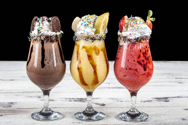Three glasses of milkshake with assorted flavors. Chocolate, ananas and strawberry milkshake. - Foto, Bild