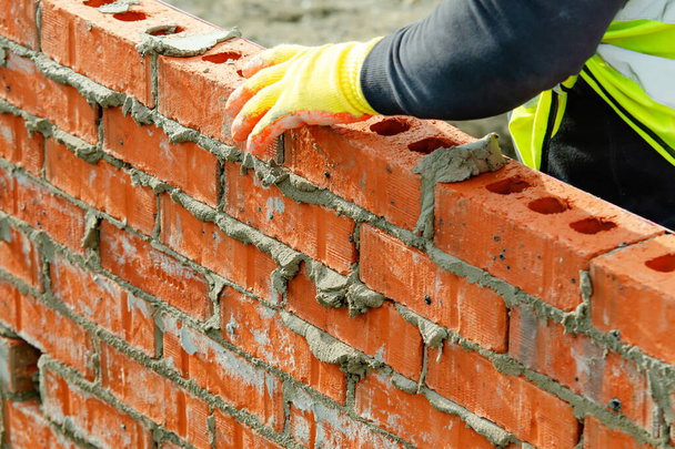 Bricklayer laying bricks on mortar on new residential house construction. Get skiils in briklaying concept - Photo, Image