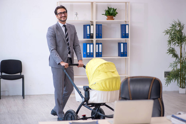 職場で新生児の世話をする若い男性社員 - 写真・画像