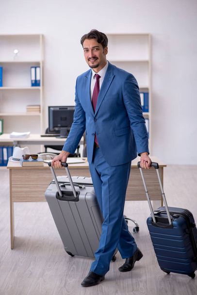 Young male employee preparing for trip at workplace - Foto, immagini