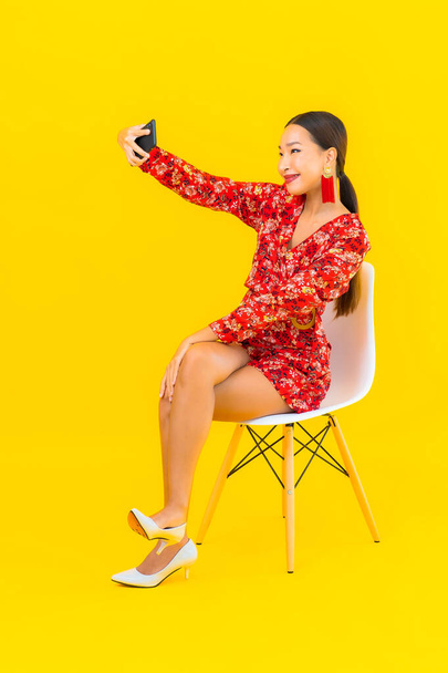 Porträt schöne junge asiatische Frau mit Smartphone auf Stuhl sitzen - Foto, Bild