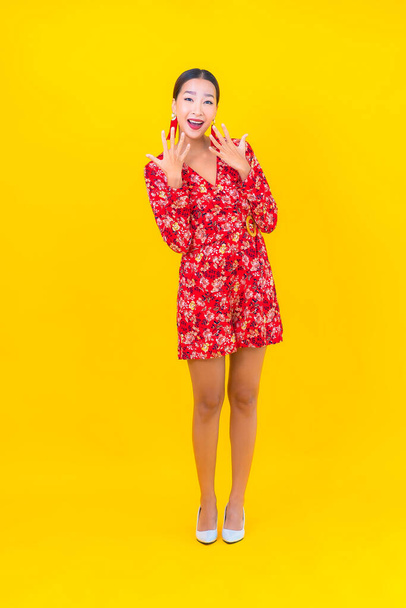 Portrait belle jeune femme asiatique sourire en action en chinois nouvelle année concept sur fond de couleur - Photo, image