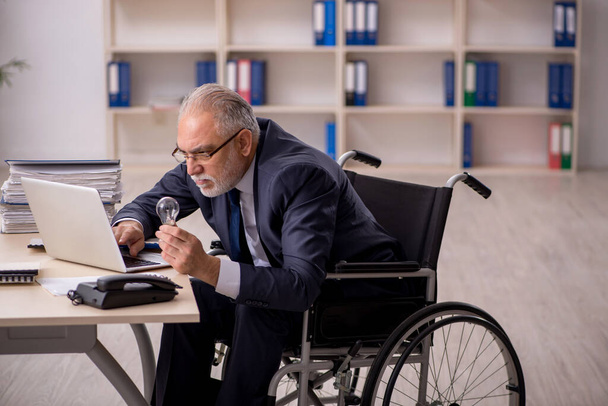 Old male employee in wheel-chair in happy idea concept - Photo, Image