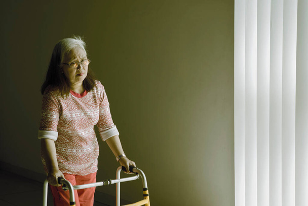 Senior woman walking with a walker after recovering from stroke disease at home - Valokuva, kuva