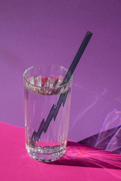 Reusable glass Straws in Glass with water on purple violet background Eco-Friendly Drinking Straw Set with cleaning brush. Zero waste, plastic free concept - Foto, afbeelding