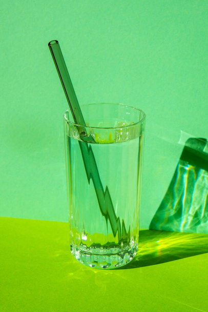 Reusable glass Straws in Glass with water on green background Eco-Friendly Drinking Straw Set with cleaning brush. Zero waste, plastic free concept - Foto, Imagen