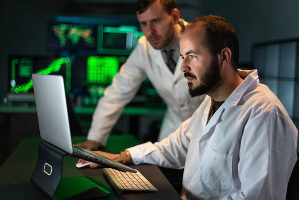 Twee mannelijke dokterscollega 's analyseren wat experimentele resultaten in de laptop. Werken in het laboratorium. - Foto, afbeelding