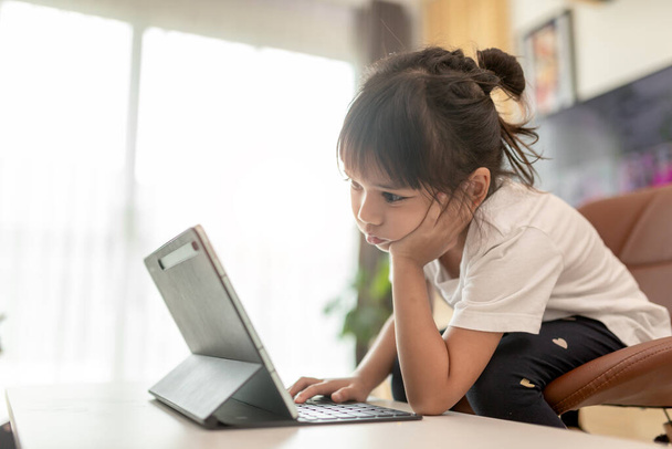Красива школярка, яка вивчає домашнє завдання під час онлайн-уроку вдома, соціальна дистанція під час карантину, самоізоляція, концепція онлайн-освіти, домогосподарка
 - Фото, зображення