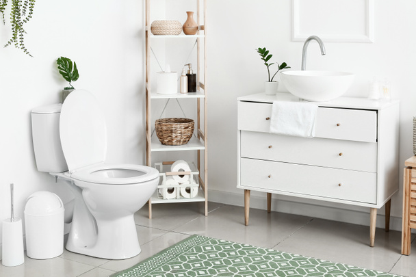 Интерьер белого туалета с унитазом и комодом - Фото, изображение