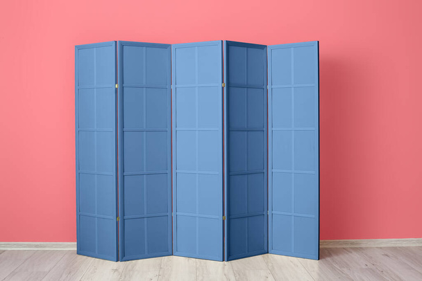 Blue folding screen near pink wall - Фото, изображение