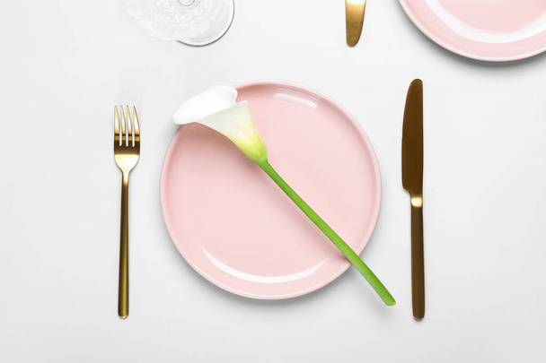 Όμορφη ρύθμιση τραπέζι με χρυσά μαχαιροπίρουνα και κρίνο calla σε λευκό φόντο, closeup - Φωτογραφία, εικόνα