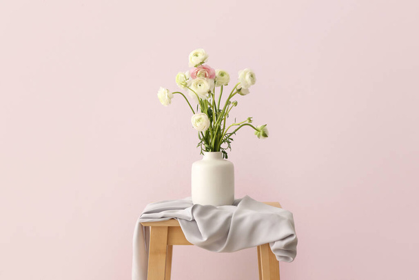 Ваза с красивым букетом цветков ранункула на столе
 - Фото, изображение