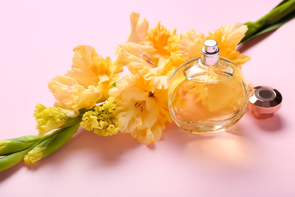 Beautiful gladiolus flowers and bottle of perfume on color background, closeup - Photo, image