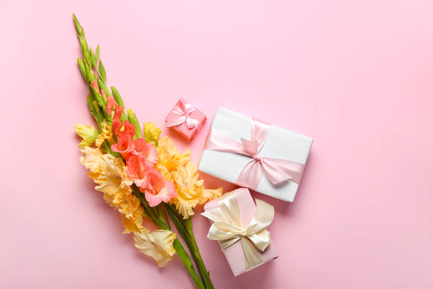 Bouquet of beautiful gladiolus flowers and gift boxes on color background - Zdjęcie, obraz