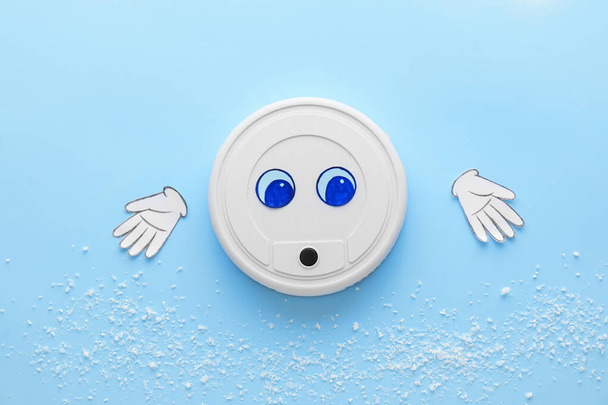 Современный робот пылесос с нарисованными глазами и бумажными руками на синем фоне - Фото, изображение