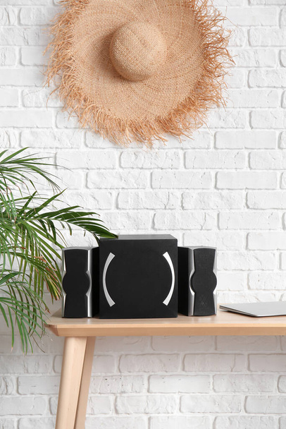 Modern speakers and laptop on table near white brick wall - Photo, image