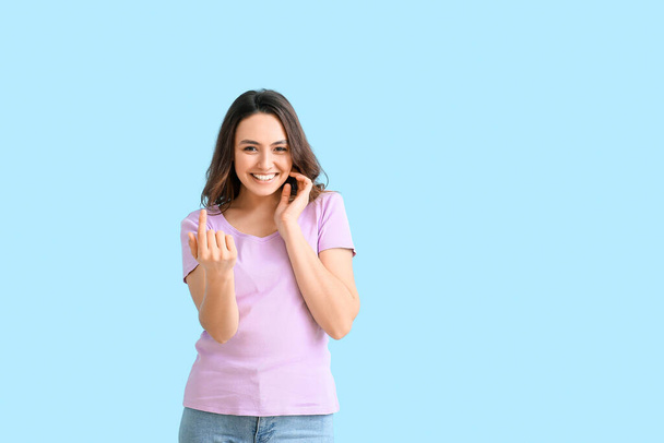 Young woman showing "come here" gesture on color background - Foto, Bild