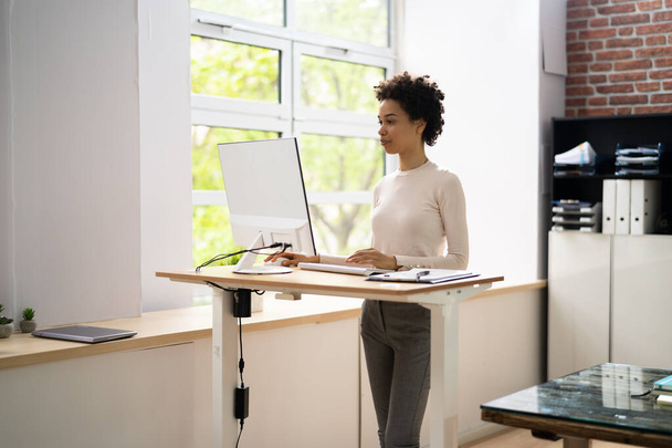 Woman Using Adjustable Height Standing Desk In Office For Good Posture - Photo, Image